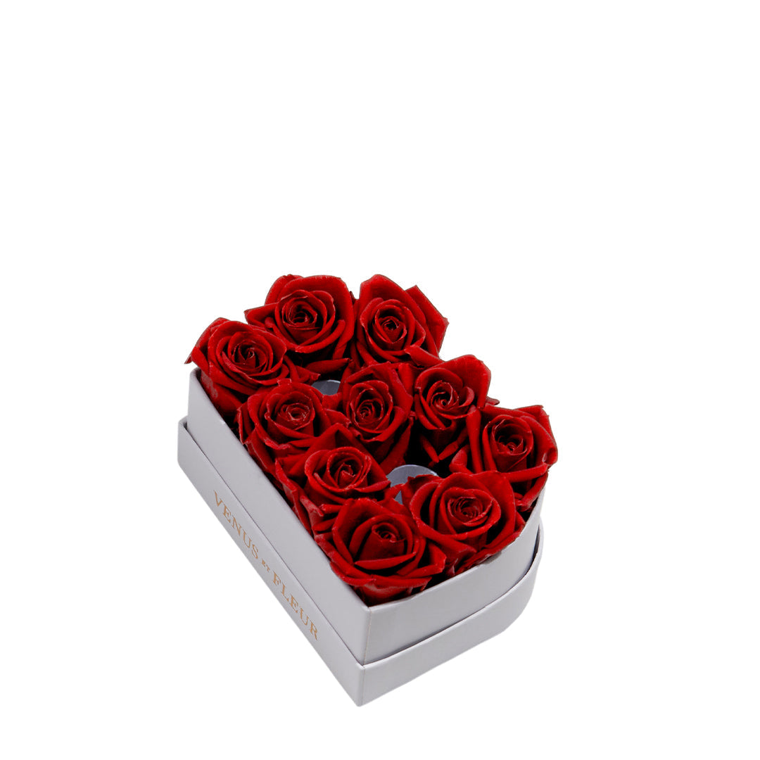 Heart-shaped box filled with nine red roses, with 'VENUS FLEUR' text visible on the side of the box.