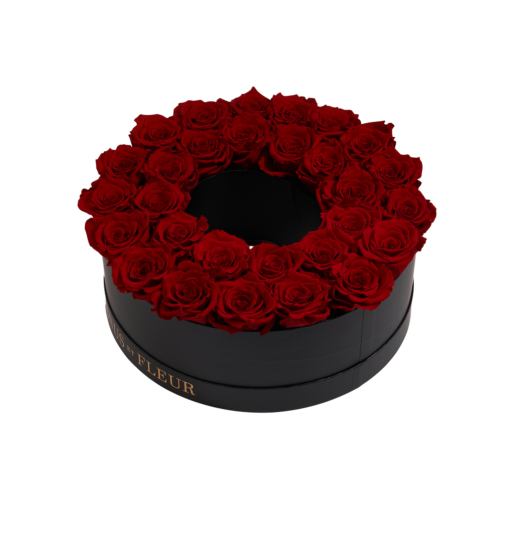 Black circular box filled with red roses arranged in a ring shape, with gold text on the side reading 'ET FLEUR'.