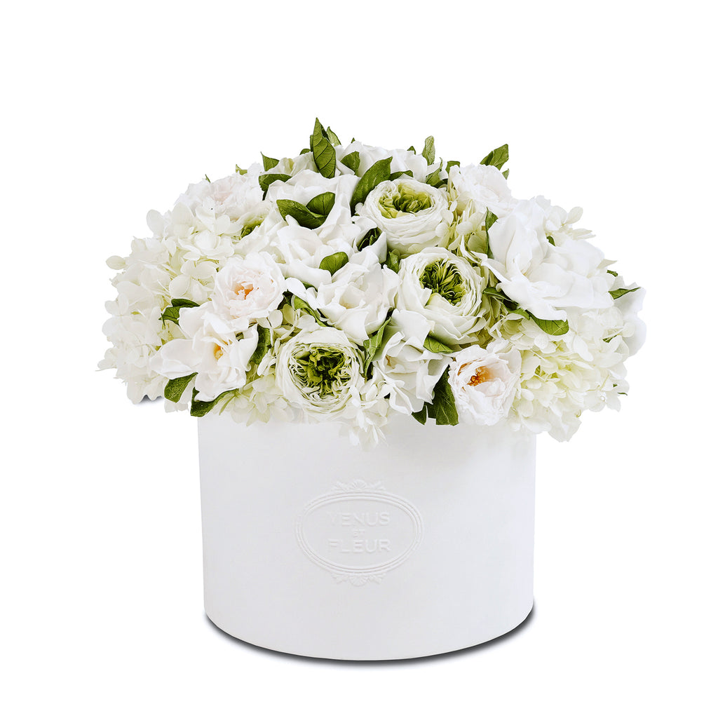 White round box with embossed text 'VENUS ET FLEUR' containing a bouquet of white and green flowers including roses and hydrangeas.