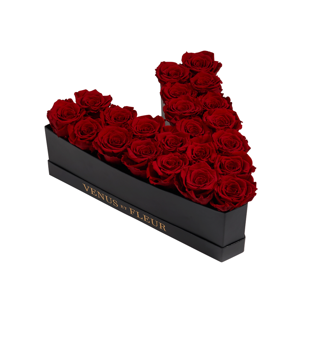 Black box with red roses arranged in a V shape, with gold text on the box reading 'VENUS ET FLEUR'