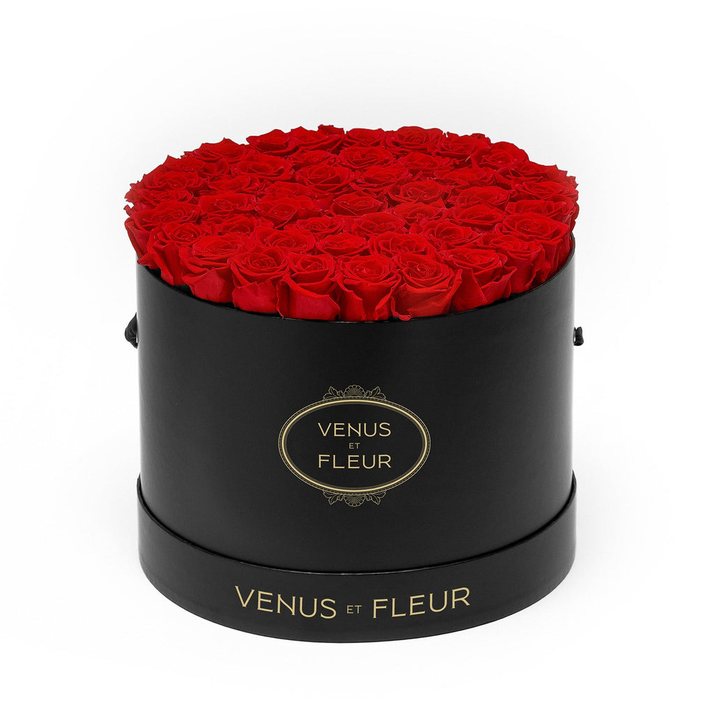 Black round box filled with red roses, labeled 'VENUS ET FLEUR'