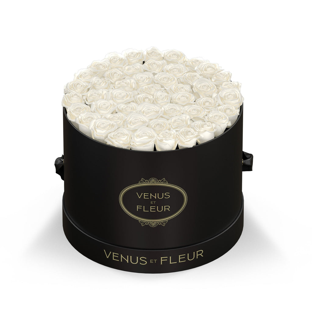 Black round box filled with white roses, labeled "VENUS ET FLEUR"