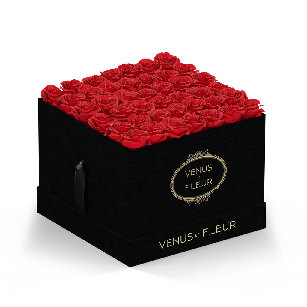 Black square box filled with red roses, branded with 'VENUS ET FLEUR' in gold lettering on the front and bottom edges.