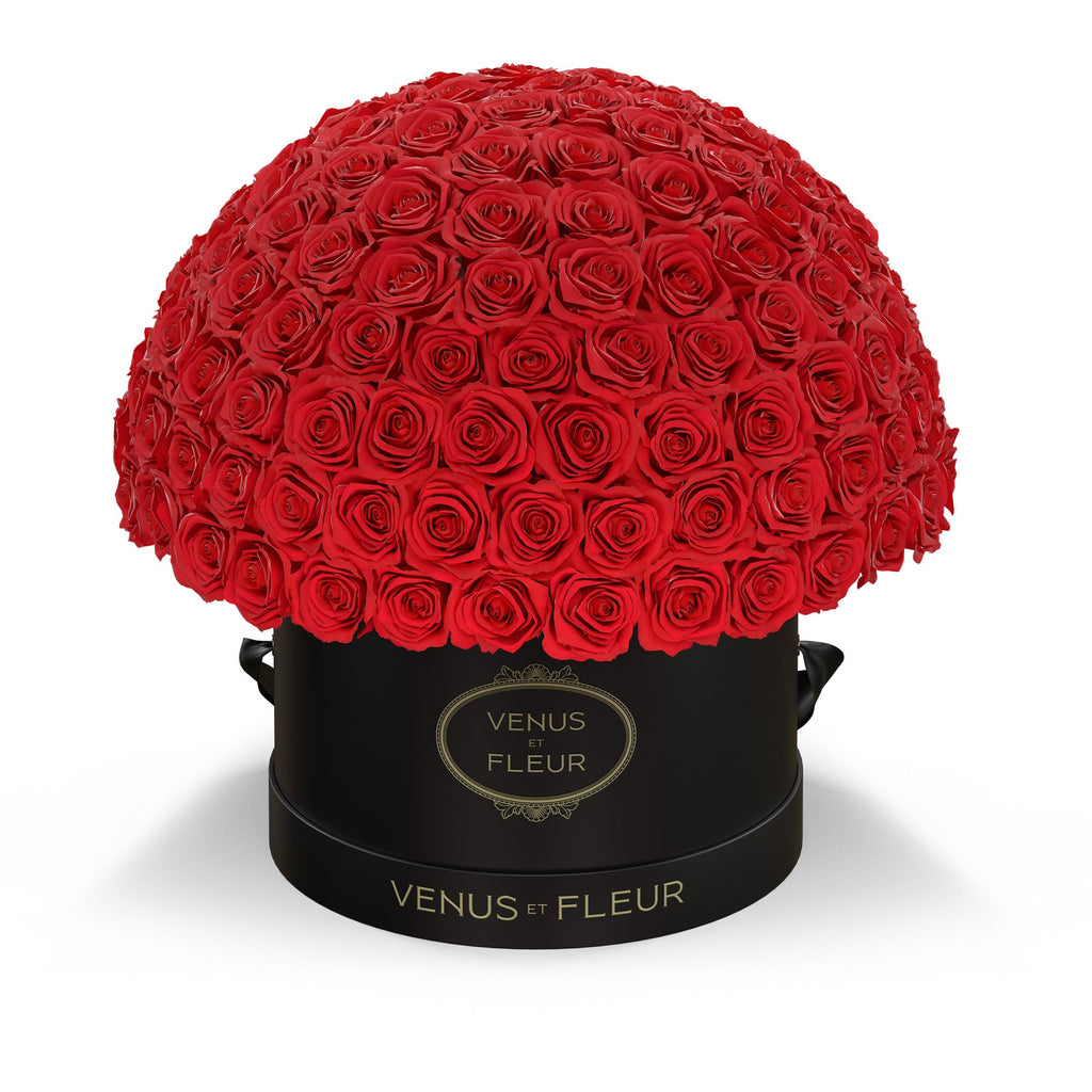 Large arrangement of red roses in a black round box with gold text 'VENUS ET FLEUR' on the box