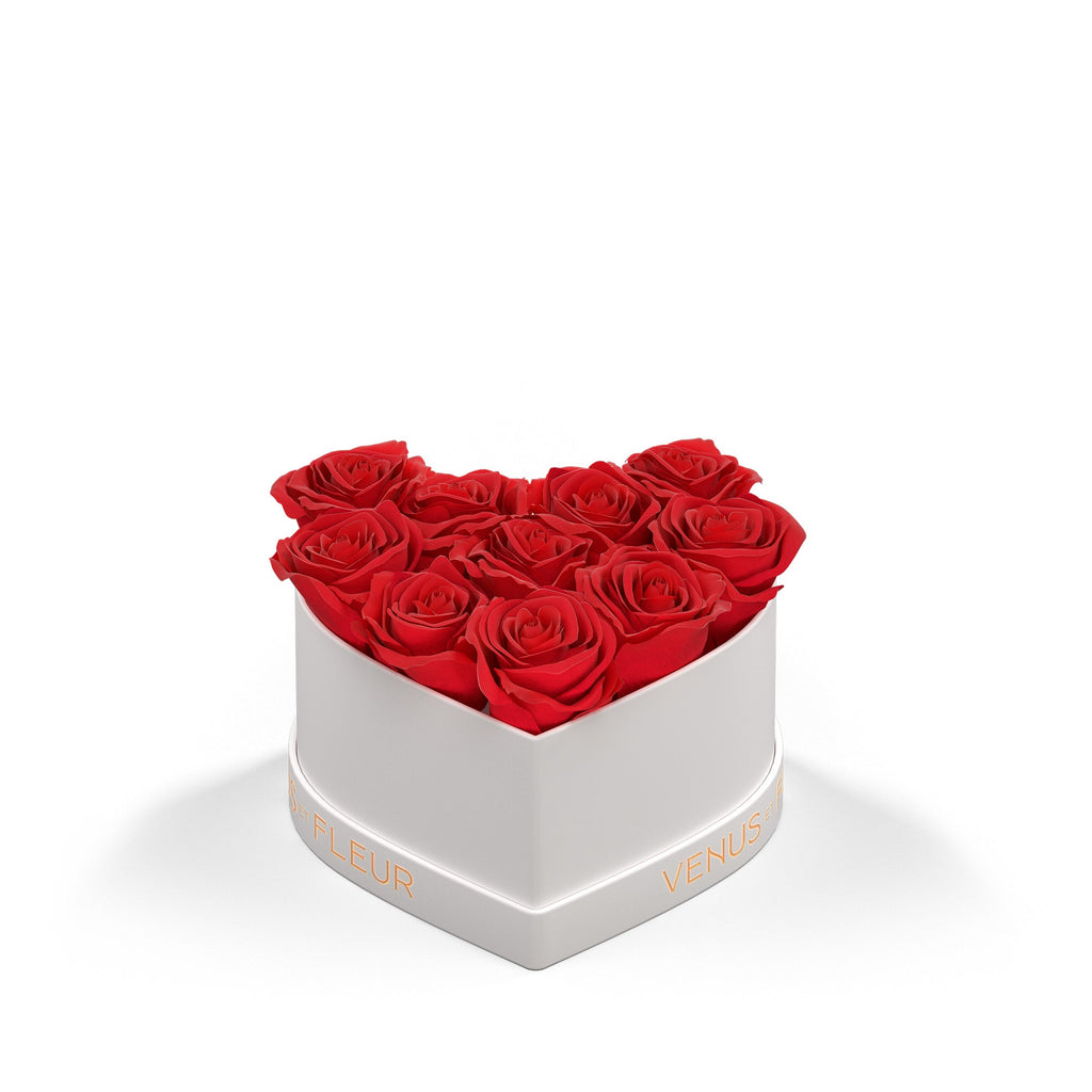 Heart-shaped white box filled with nine red roses, with the text 'VENUS ET FLEUR' in gold on the box's side.