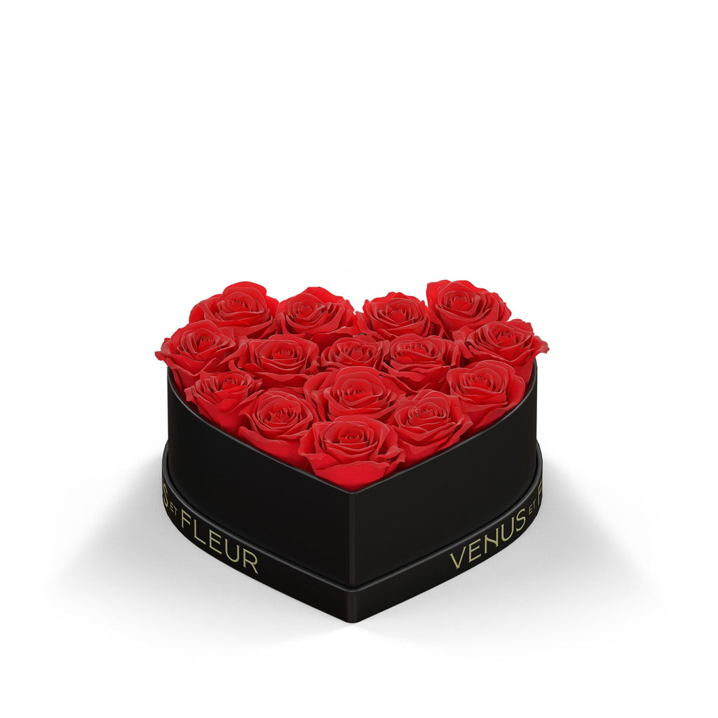 Heart-shaped black box filled with 15 red roses, with "VENUS ET FLEUR" text on the box.