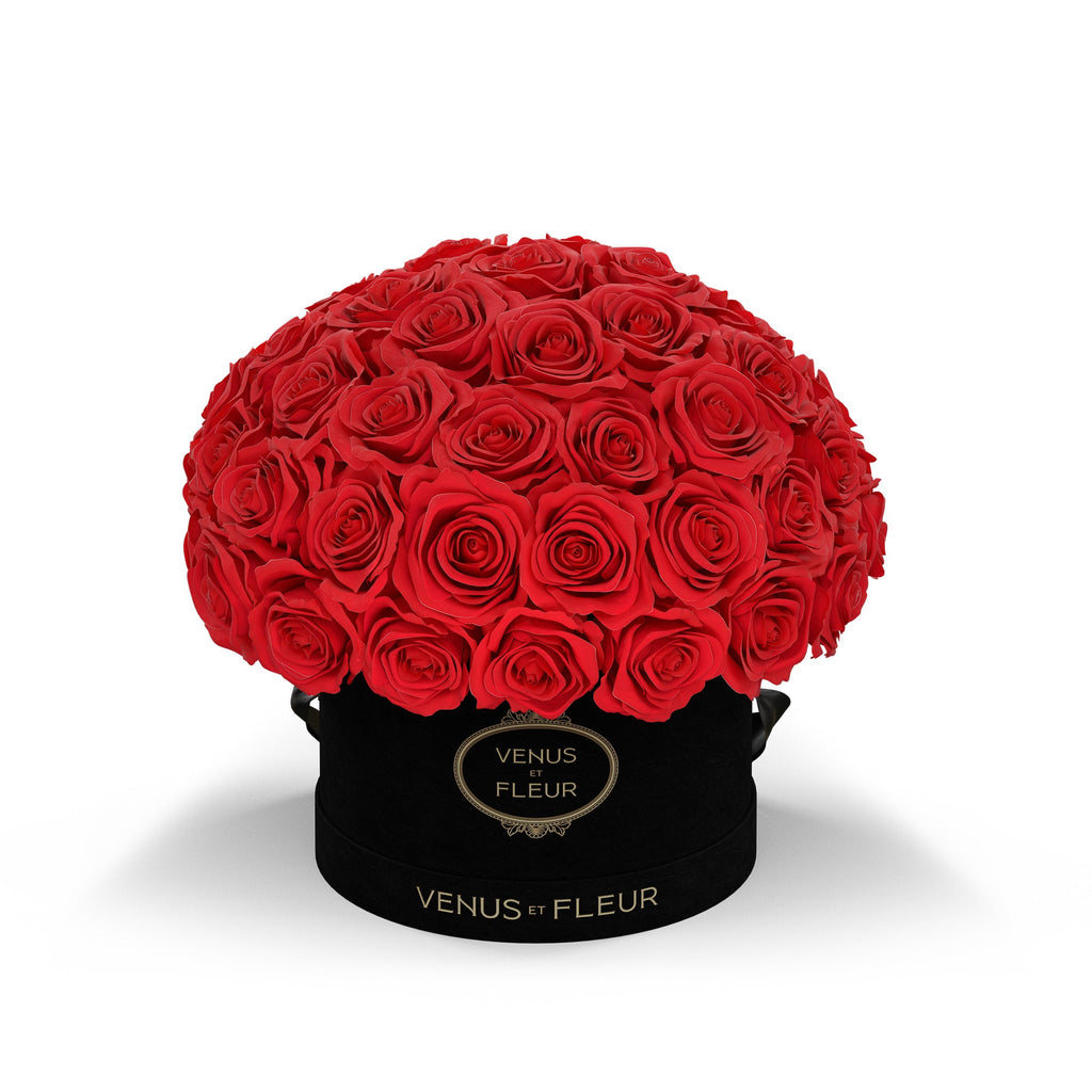 Bouquet of red roses in a black round box labeled 'VENUS ET FLEUR'