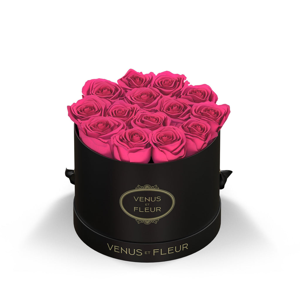 Black round box with bright pink roses arranged inside, labeled 'VENUS ET FLEUR'
