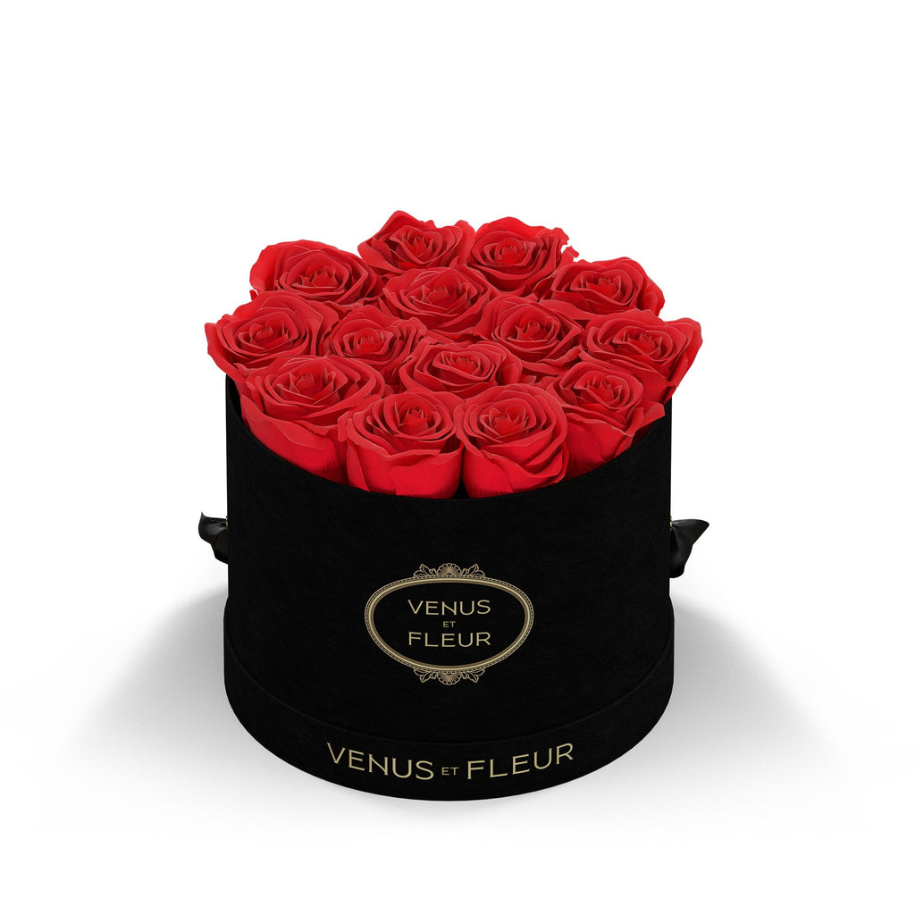 Black round box filled with red roses, labeled 'VENUS ET FLEUR' on the front and base.