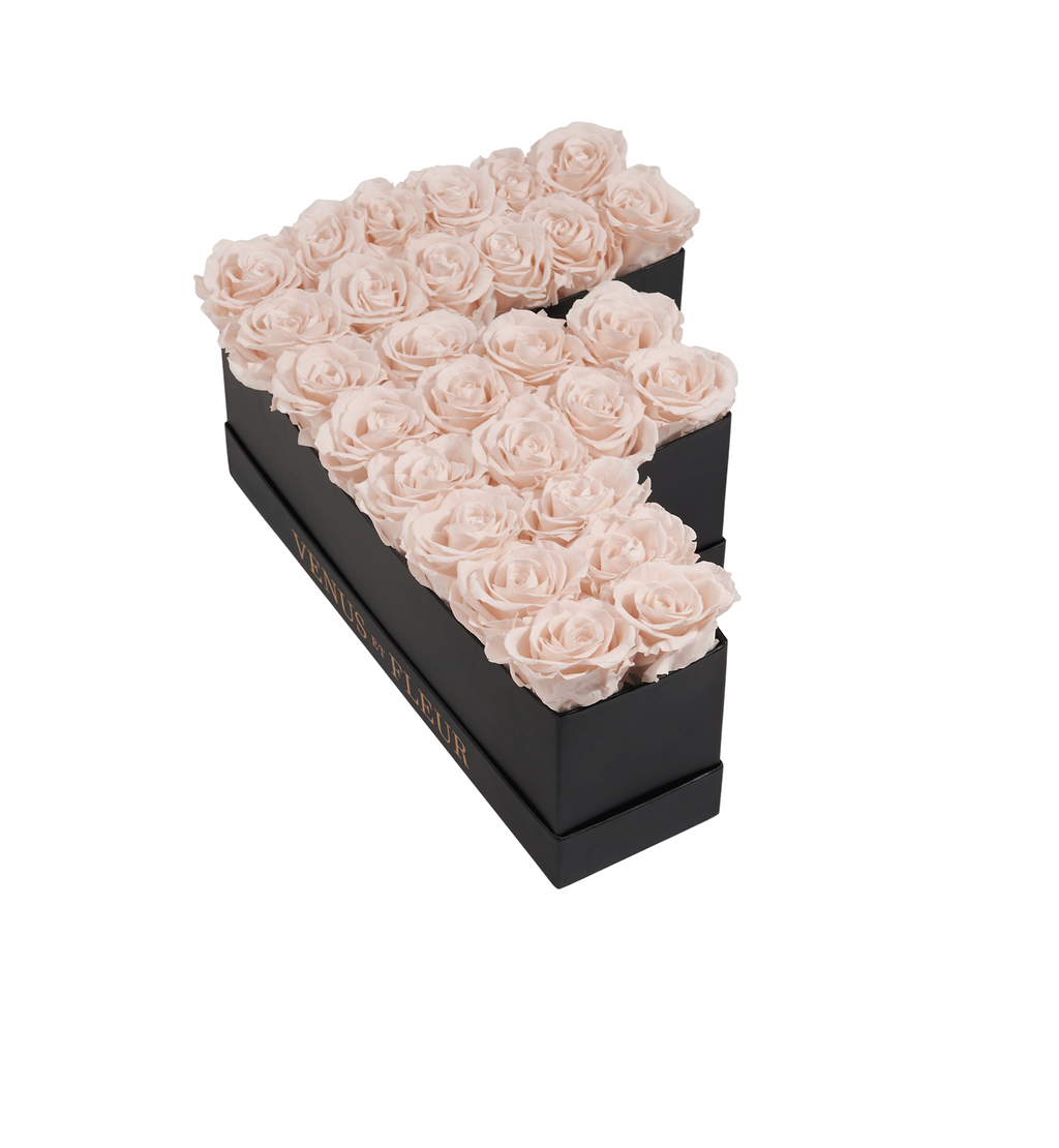 Black rectangular box with pale pink roses arranged in the shape of the letter F. The box has the text 'VENUS ET FLEUR' on the side.