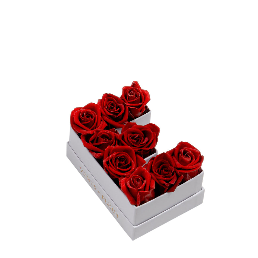 White box with red roses arranged in the shape of the letter E, with the text 'VENUS ET FLEUR' on the side of the box.
