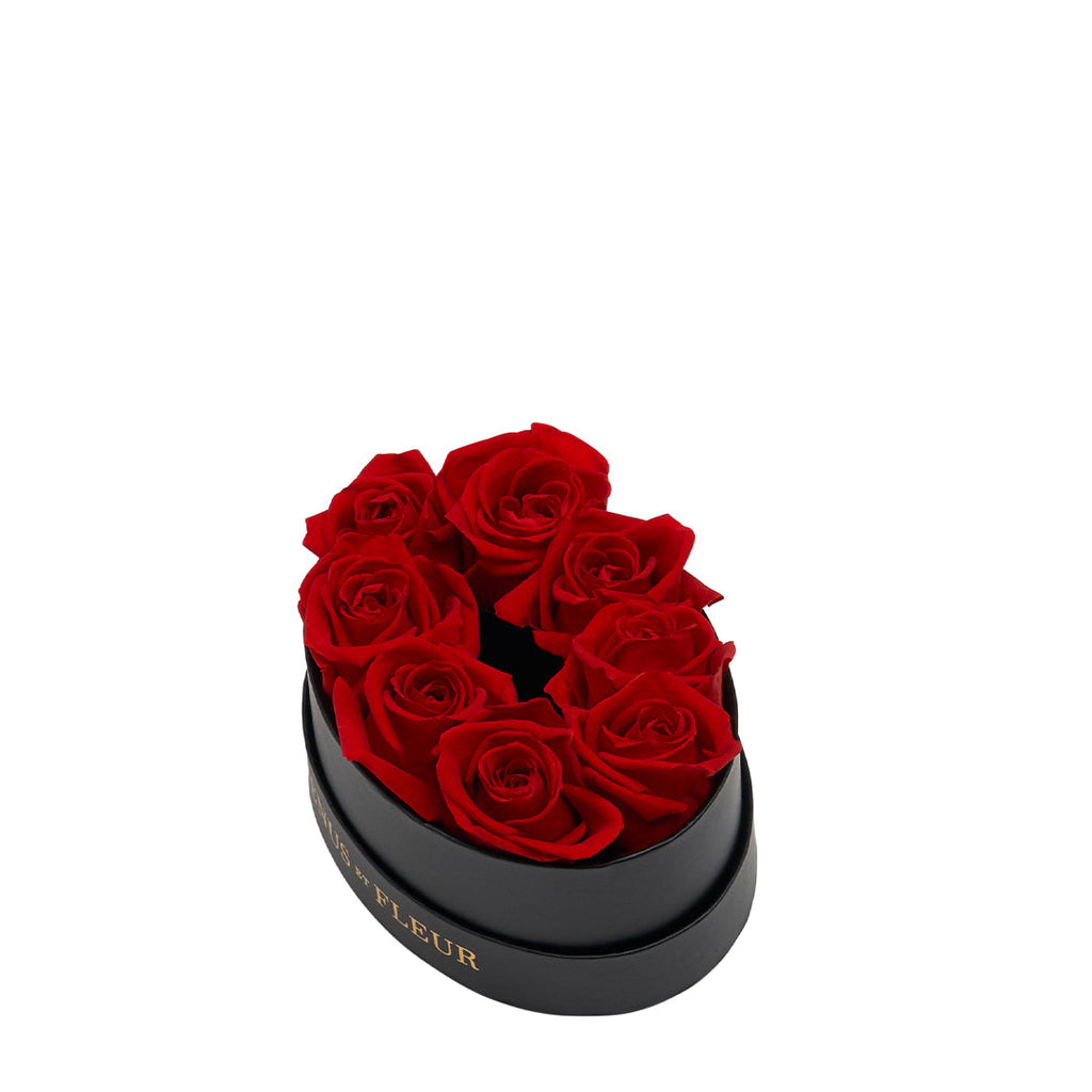 Black oval box with seven red roses arranged inside, with gold text on the side reading "FLEUR".