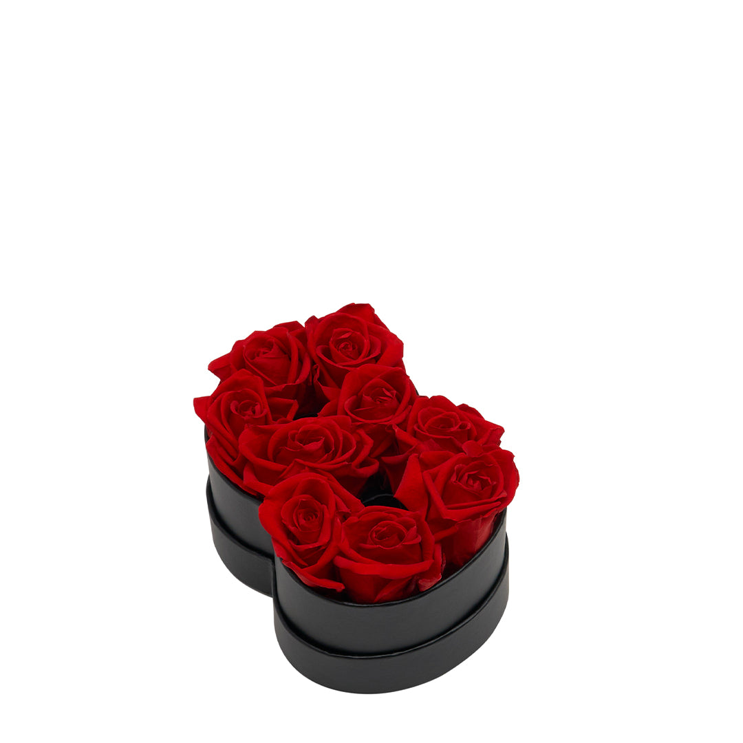 Black heart-shaped box containing eight red roses